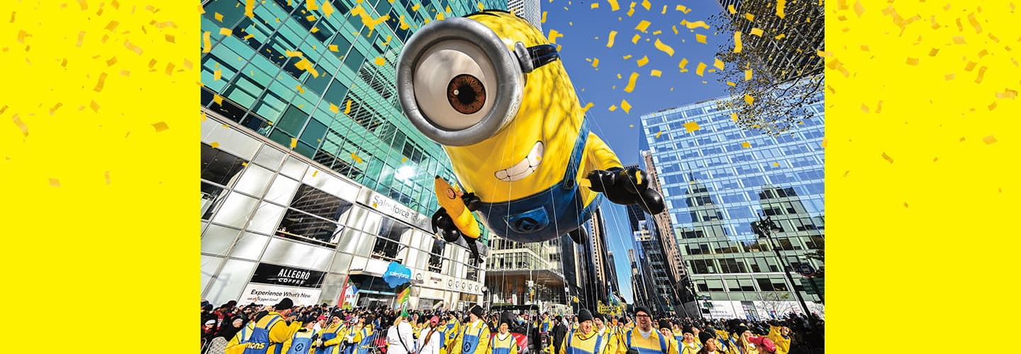 a large minion balloon soaring over a crowd